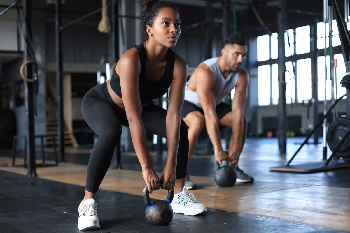 Fit and muscular couple focused on lifting a dumbbell during an exercise class in a gym